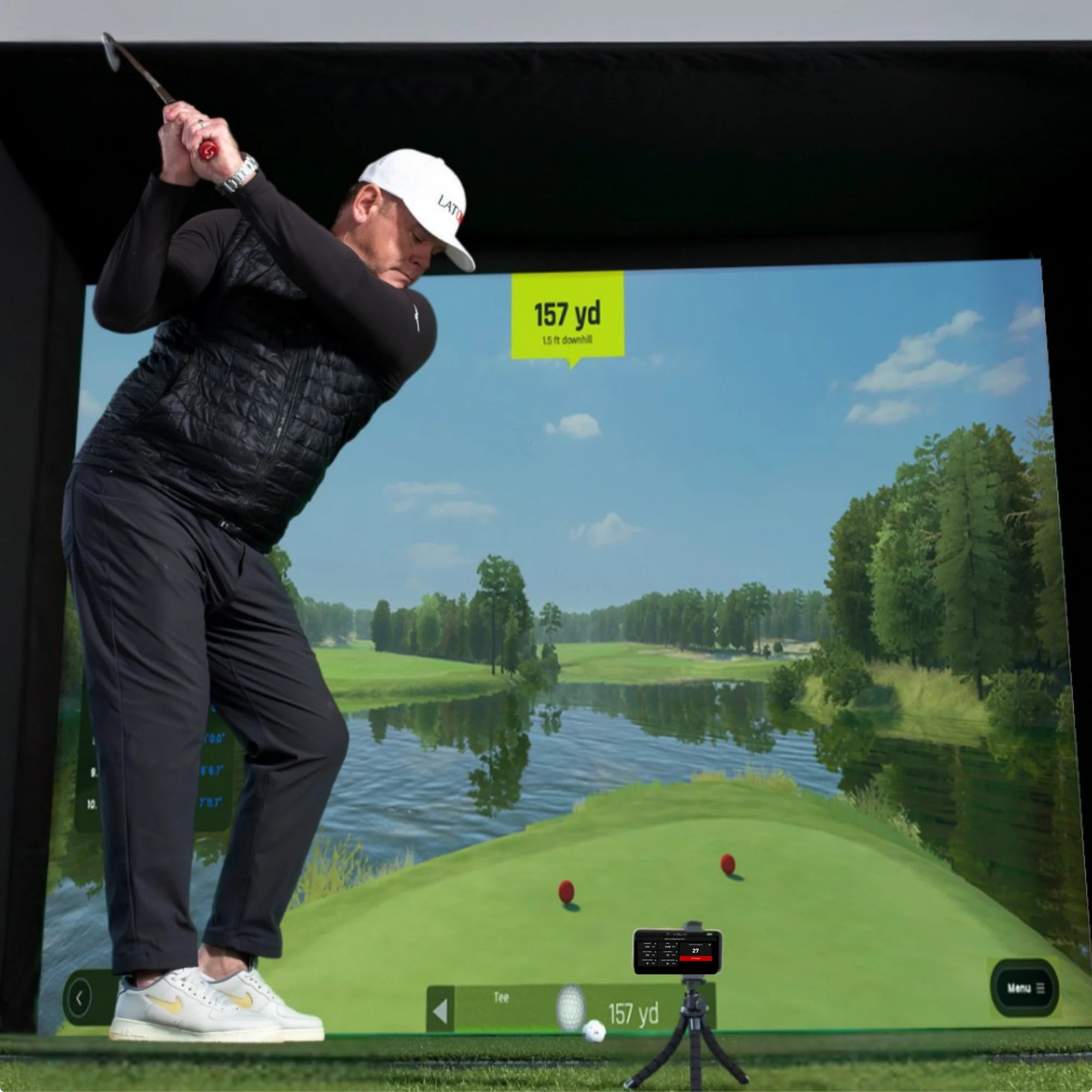 Person playing golf on a simulator with a scenic background
